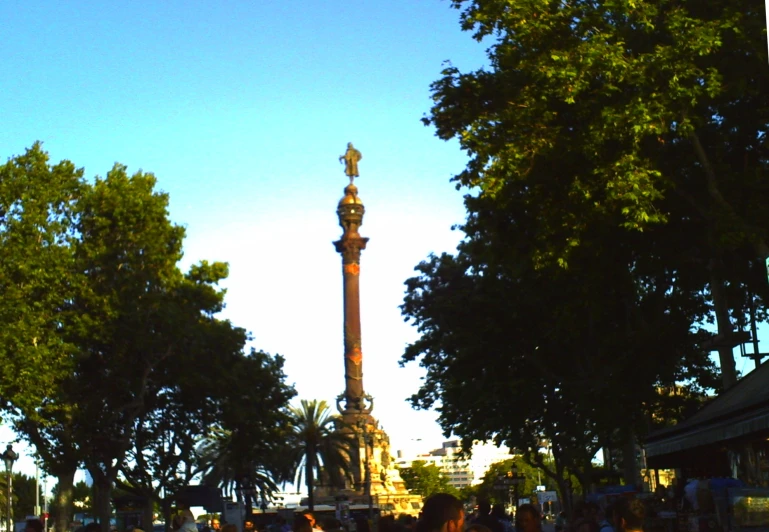 people are walking around a statue on the park