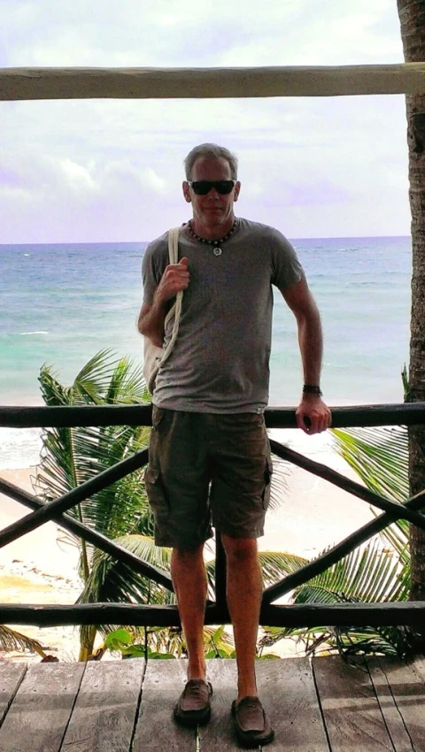 the man is standing in front of the ocean on the boardwalk