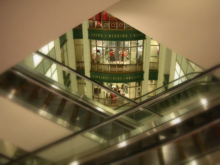 an image looking up at two escalators with store displays