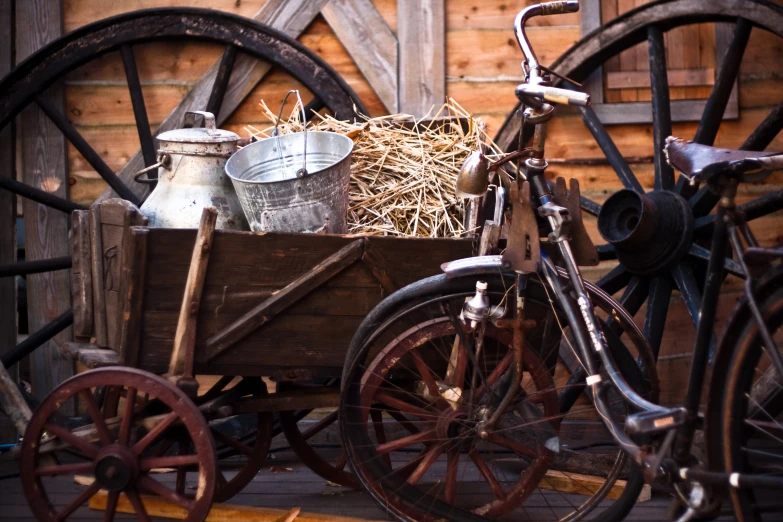 a wagon and two bicycles that have been placed in front of a wooden fence