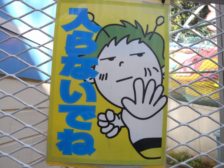 a sign attached to a fence with a picture of a cartoon character