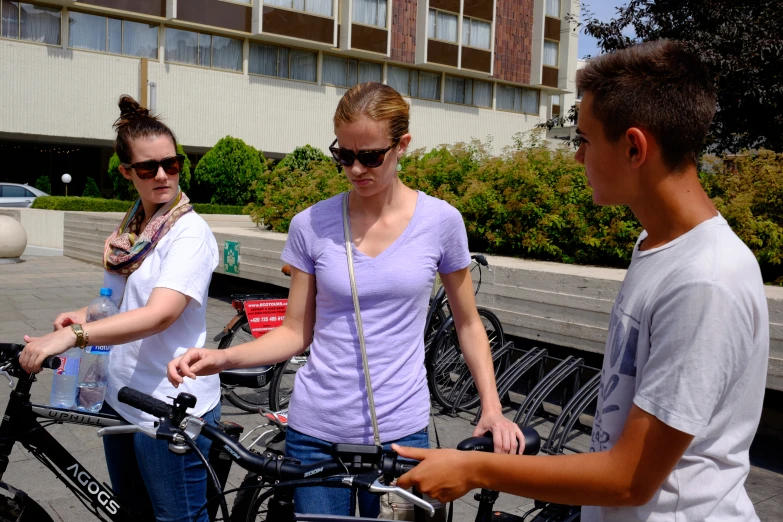 three people are standing around a bicycle with some drinks in it