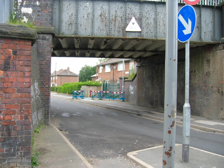 a blue street sign sitting next to a metal bridge