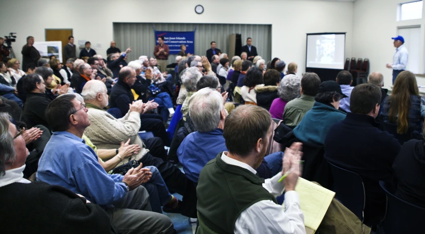 there is an audience clapping as a man speaks to the crowd