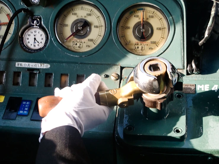 a man holding onto a valve near gauges on a plane
