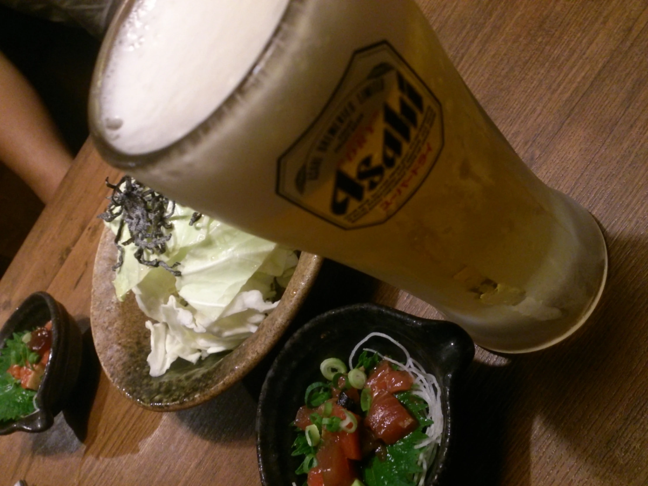 a glass sitting next to bowls of food on a wooden table