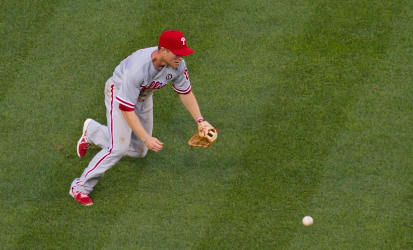 a baseball player catching the ball on the grass