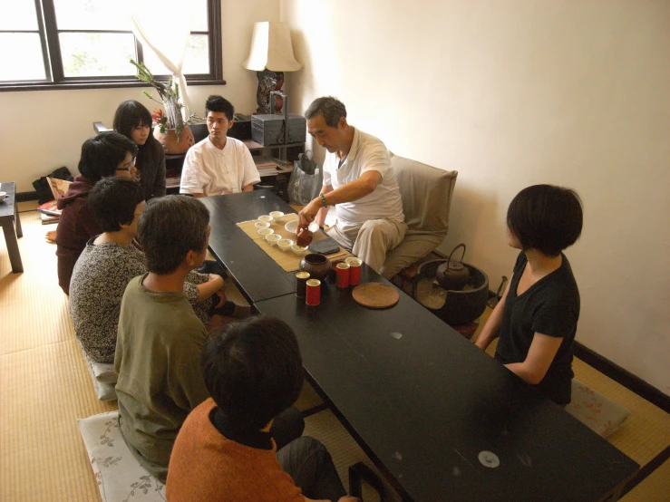 a group of people sitting around a black table with food on it