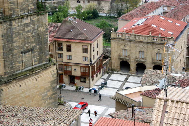 the view from atop shows a stone building and several buildings with red roofs, with an umbrella in front of it