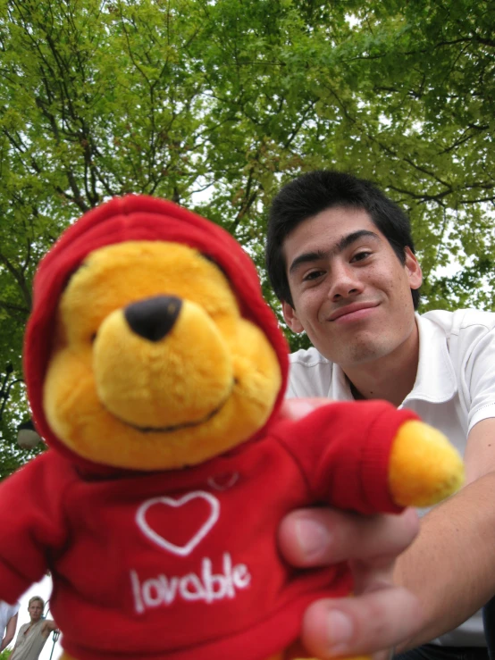 a man holds a stuffed toy and smiles