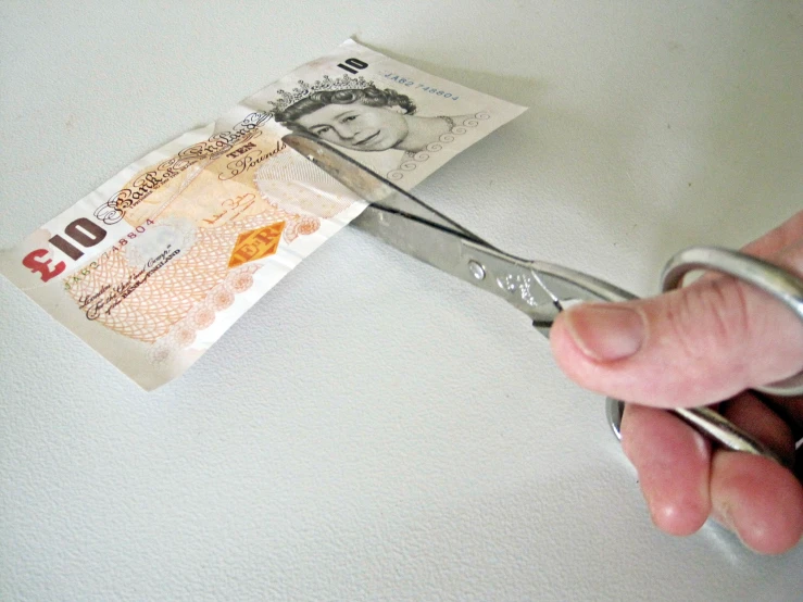 a person  money with a pair of scissors