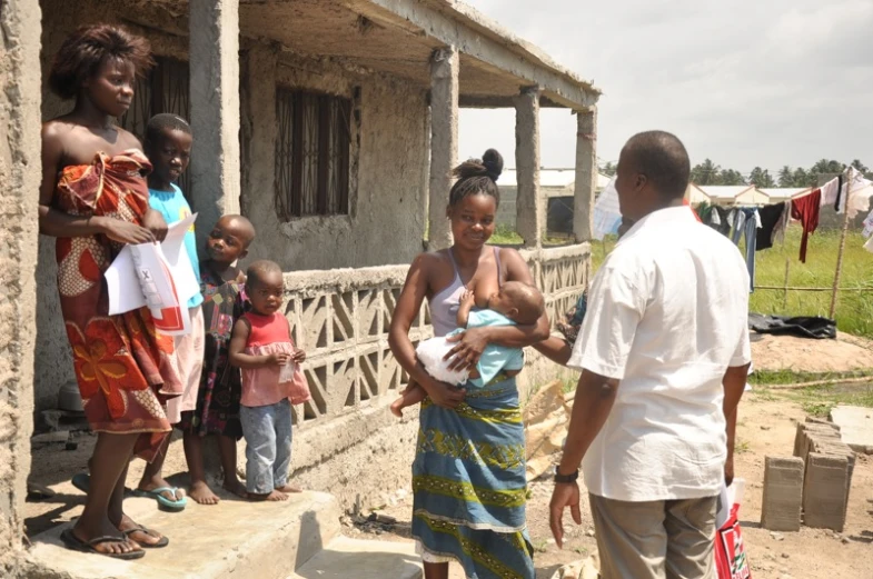 a group of people standing around a little house