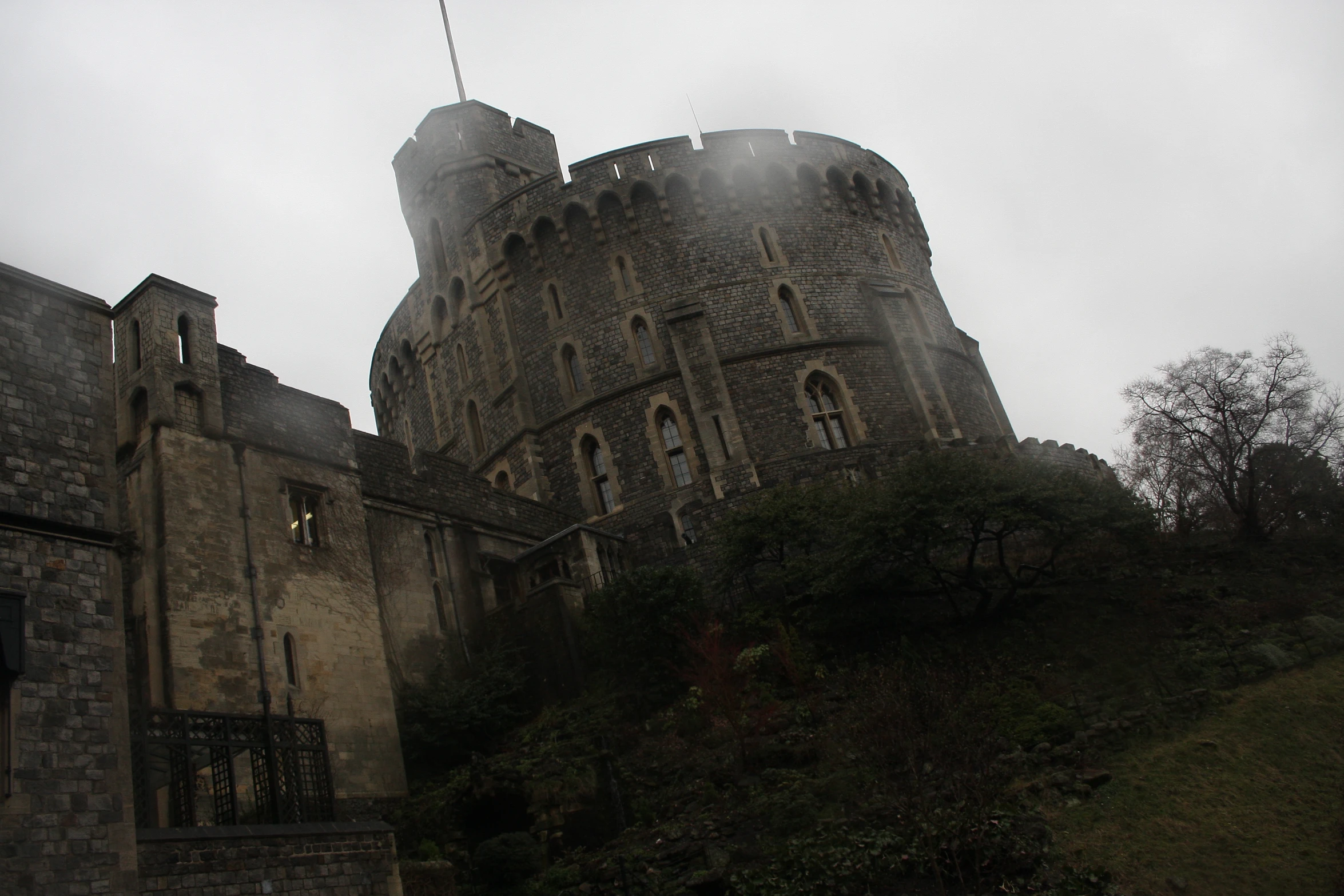 castle like building surrounded by steep hill and fog