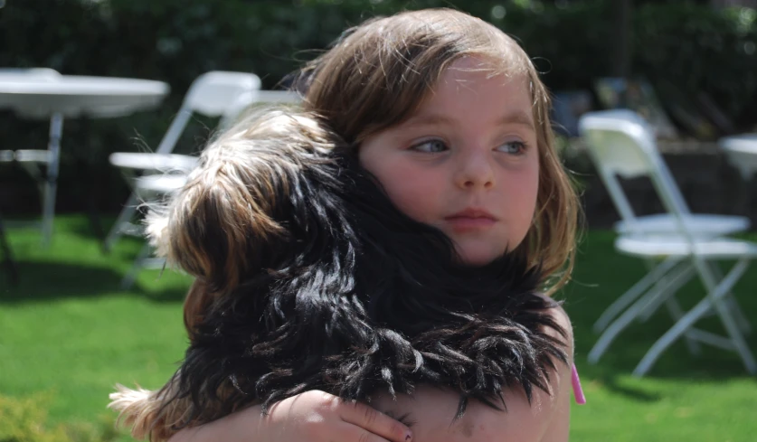 a little girl is holding a fluffy furry dog