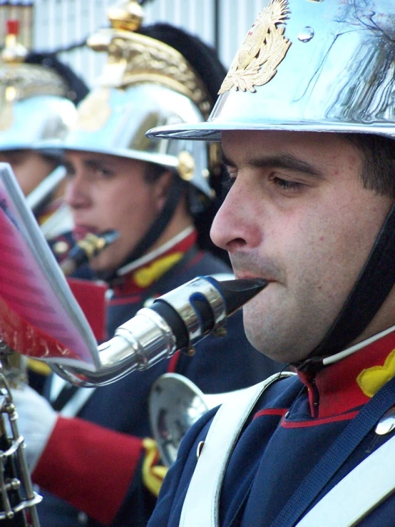 the marching players wearing helmets and uniforms are playing their instruments