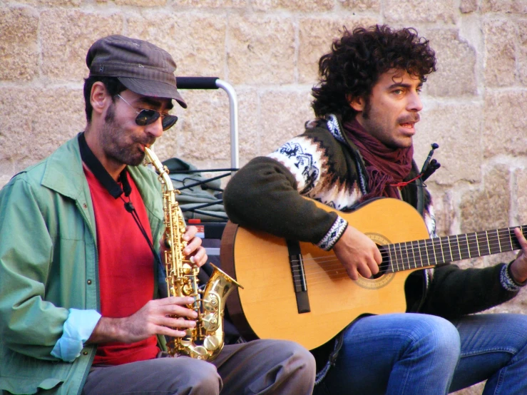 a man sitting next to another man holding an instrument