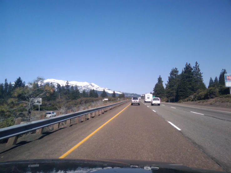 two trucks travelling down a freeway near a mountain