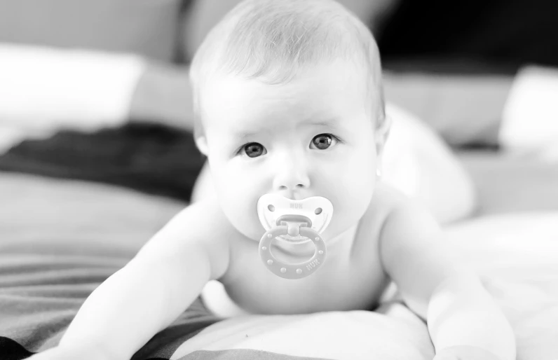 a baby laying on a blanket with his pacifier up