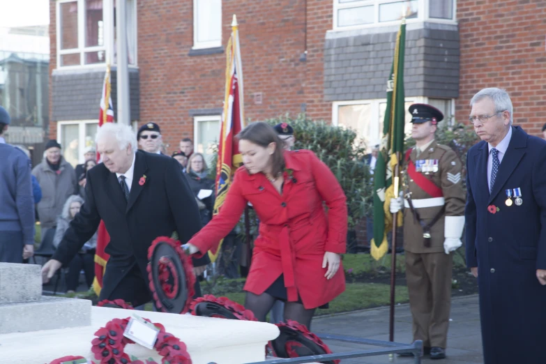 a woman walking beside wreaths near other men