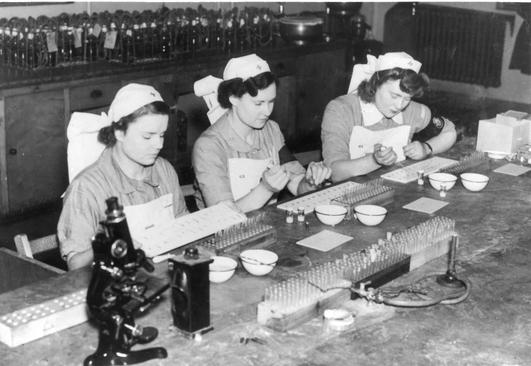 three women are working at the table, each holding a piece of paper