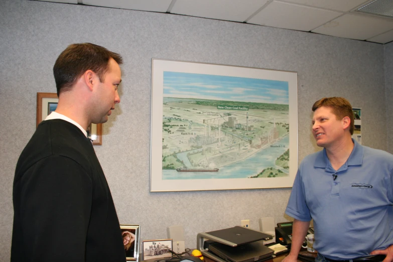 a man talking with another man in front of a wall