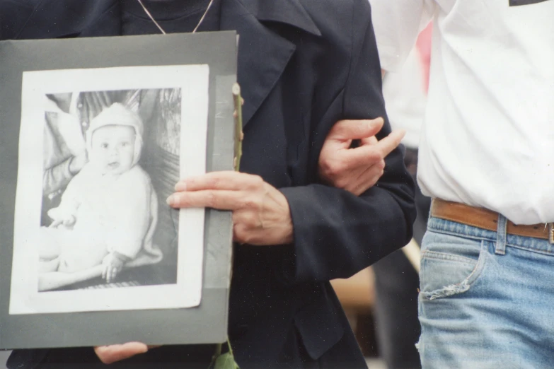 a man in black jacket holding up a picture with child