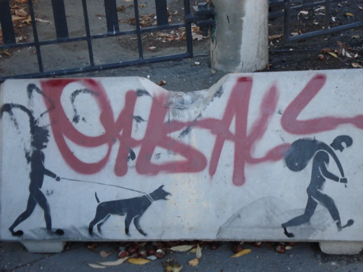 graffiti on white sign with dog pulling person in red and black