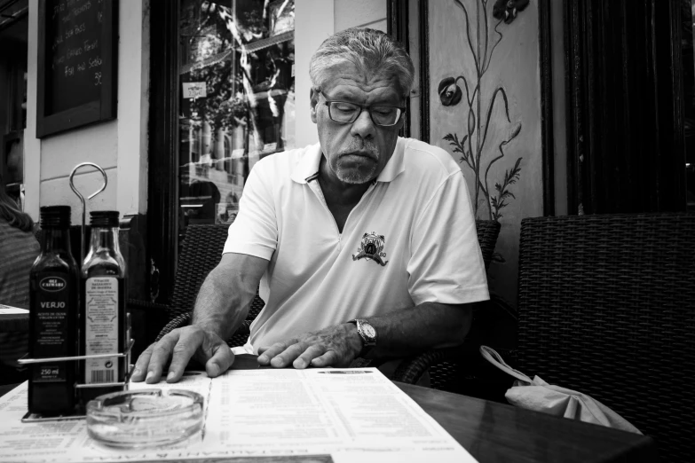 a man in glasses writing at a table in a restaurant