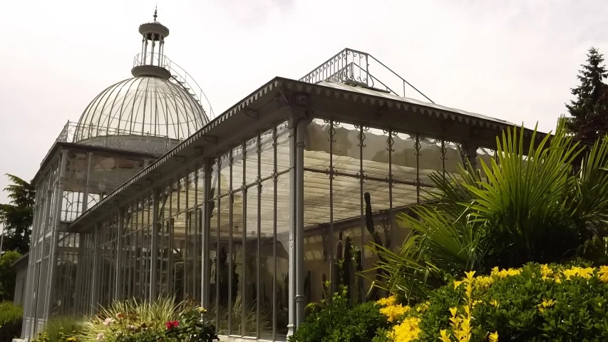 a small glass greenhouse in the middle of a park