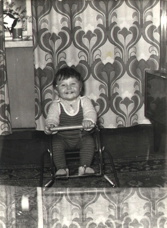 an old black and white po of a little baby sitting in a child's high chair