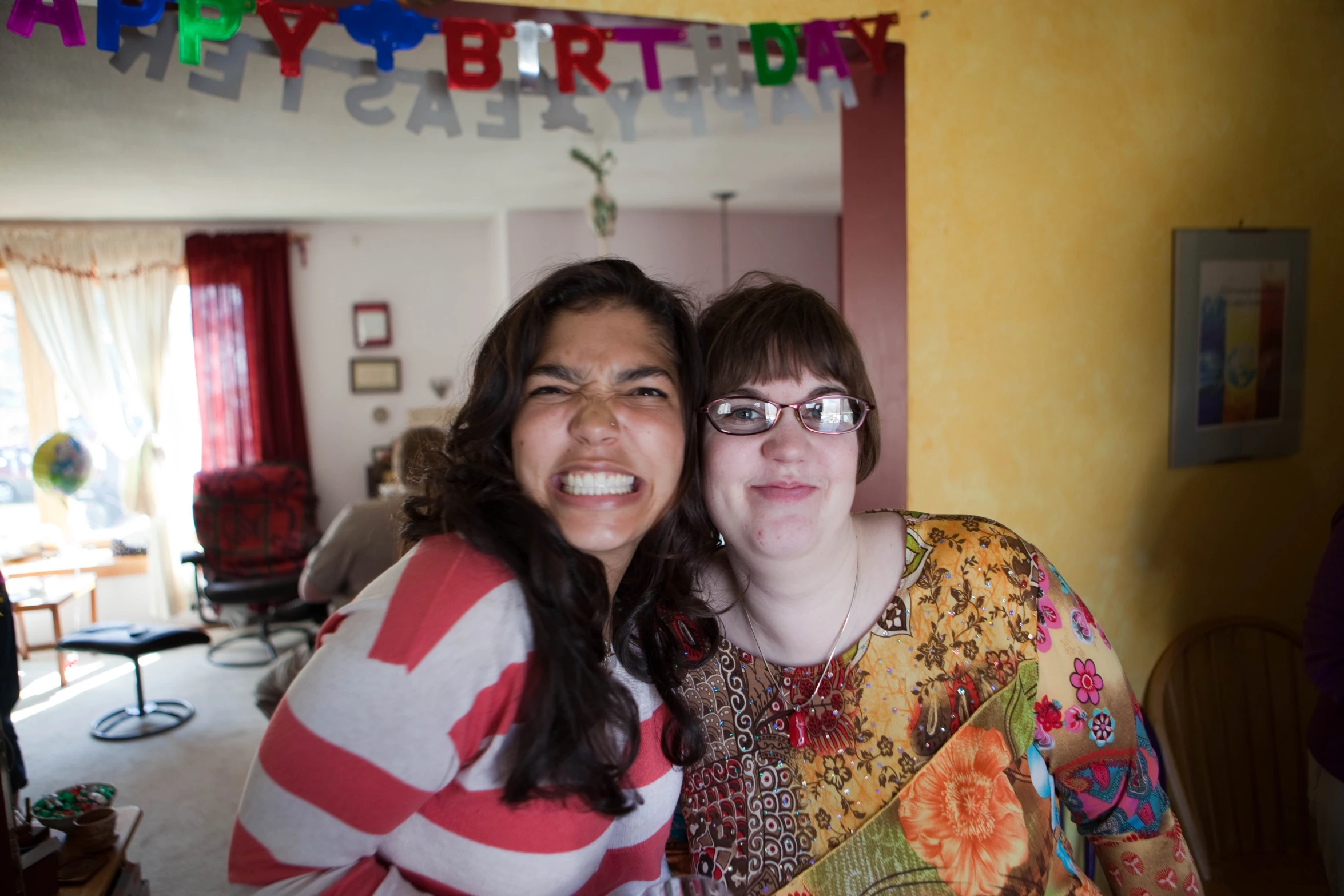 two women are standing together in the living room