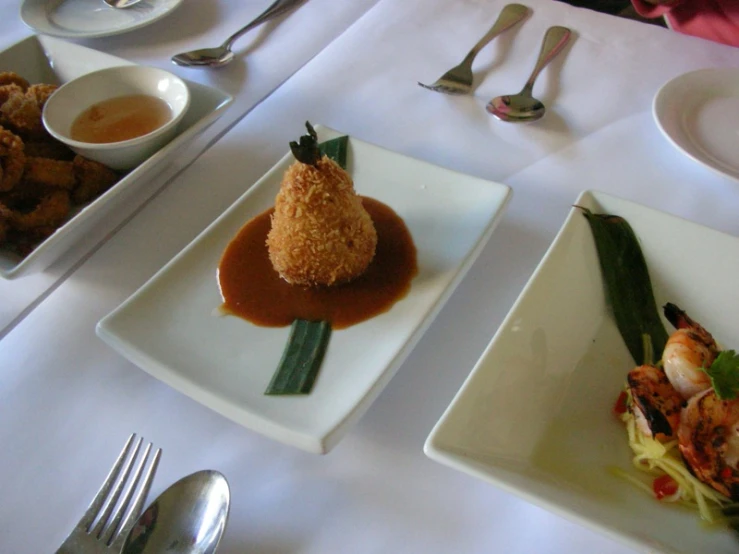 there are two square plates with food and utensils on the table