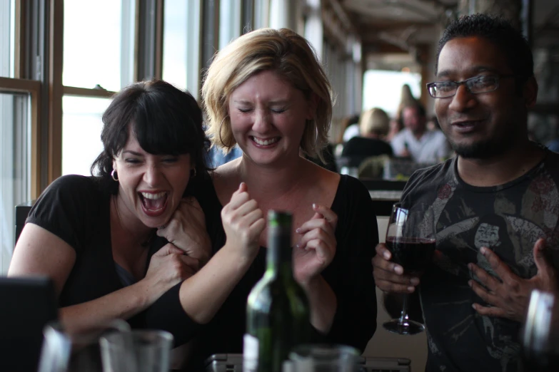 there are three people laughing and drinking wine