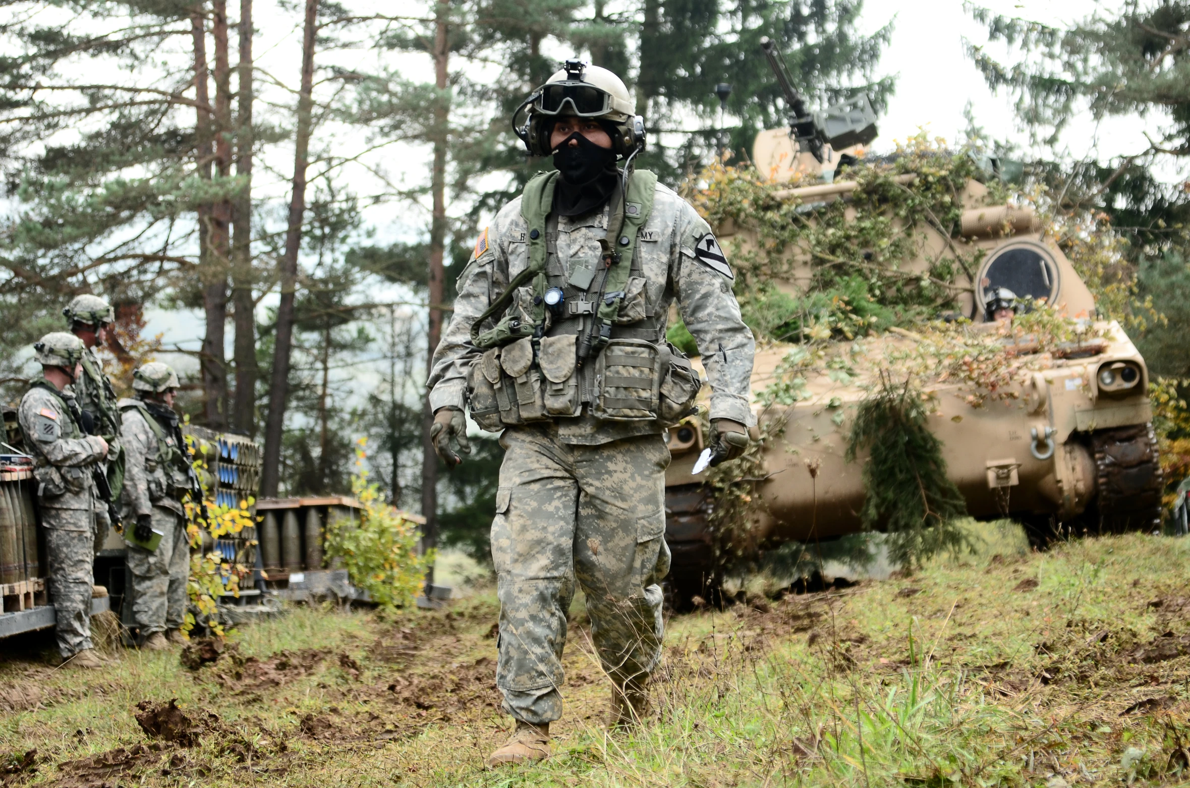 soldiers walking on the hill in front of a military vehicle