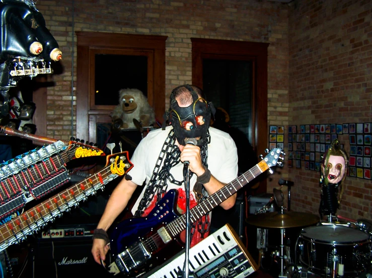 a man standing in front of guitars while wearing a mask