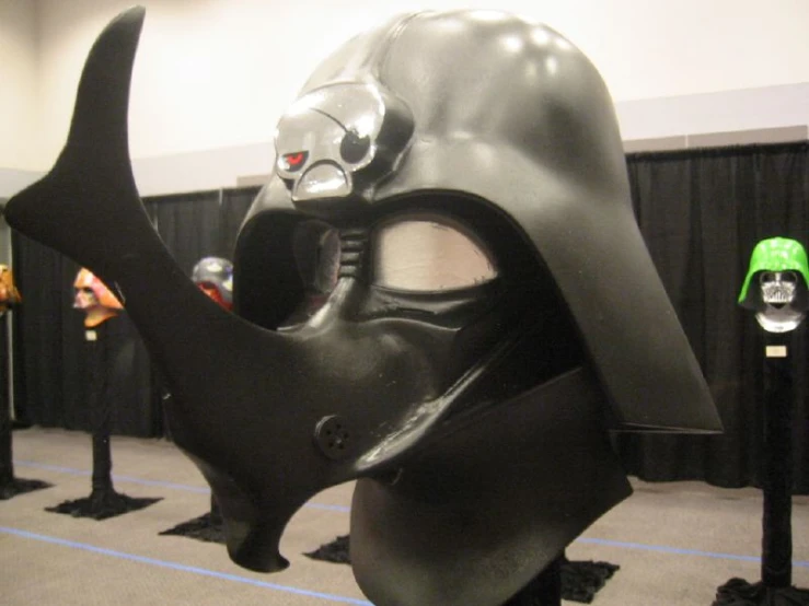 a black darth vader mask with two other black helmets on a stage