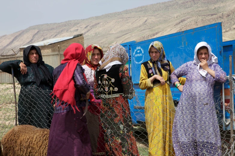 a group of girls stand near a fence