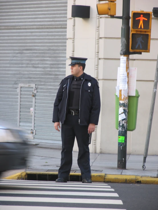 man dressed in police clothes standing at the corner of a street