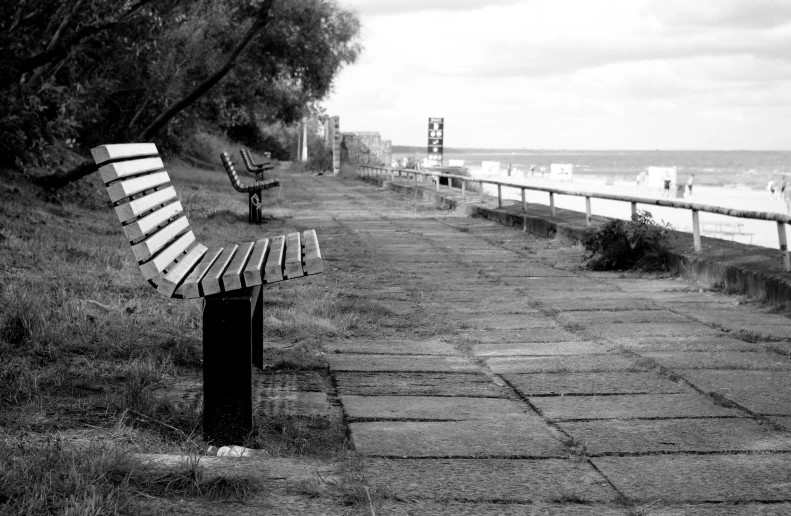 there is an empty bench in a field by the ocean