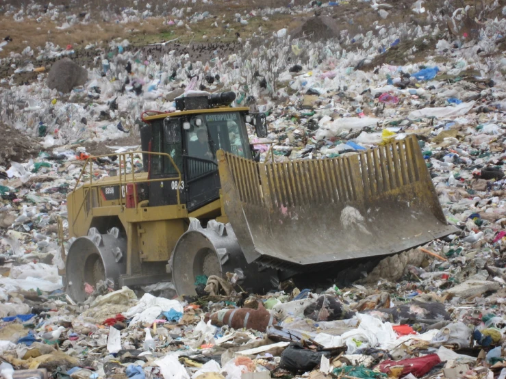 a bulldozer scoops garbage into a large pile