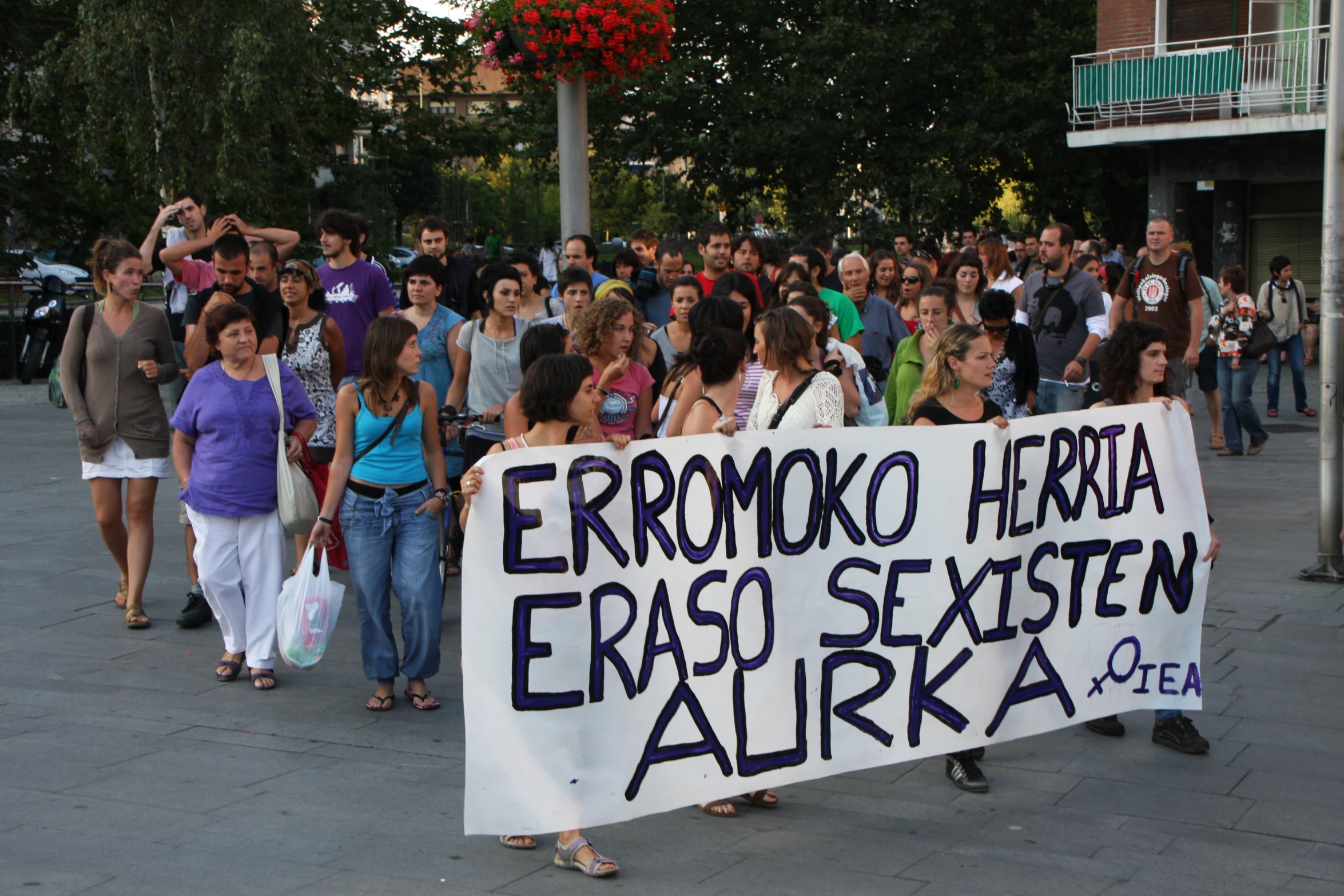 a group of people standing on the sidewalk with signs