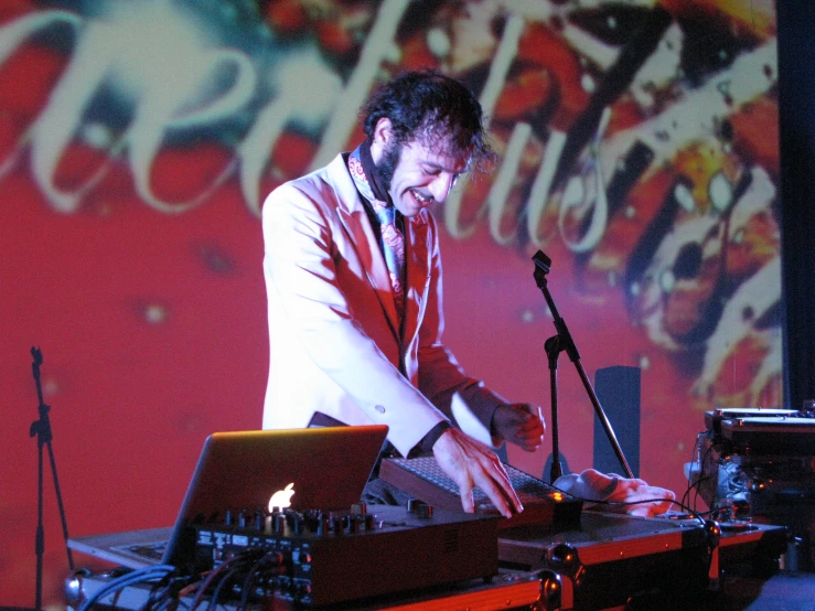 a man with a beard wearing red is playing keyboard