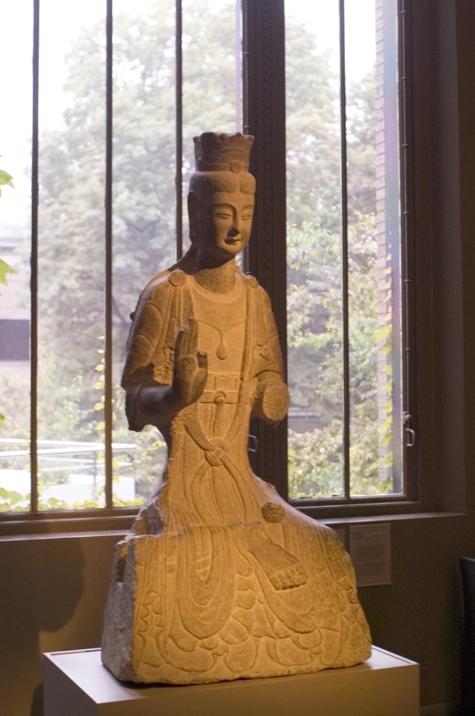 a large white statue sitting on top of a table next to a window