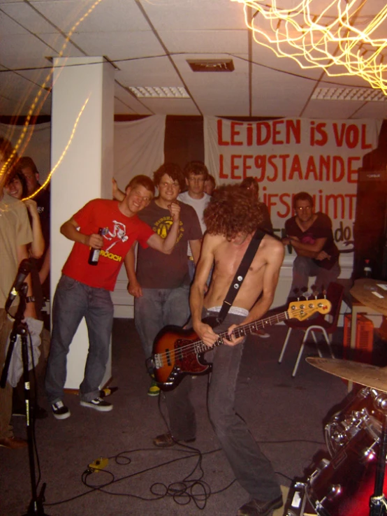 a group of young men are gathered together playing guitars