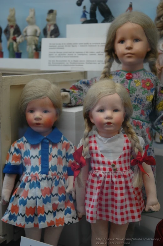 two doll standing next to each other with a picture of an older girl