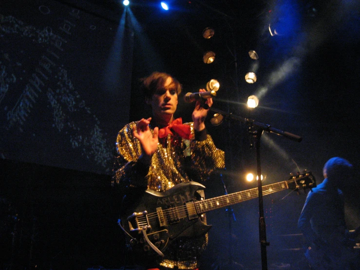 a person standing in front of a microphone holding a guitar