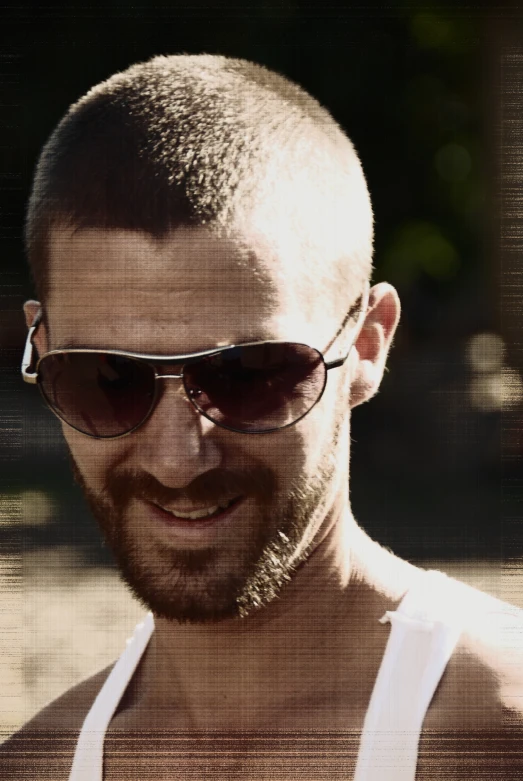a man wearing sunglasses has a beard and looks to his left