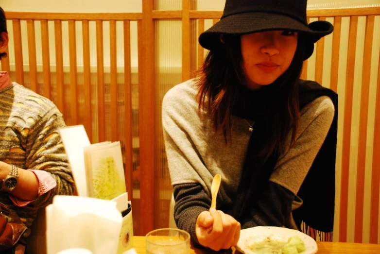 a woman wearing a hat at a dinner table with a man