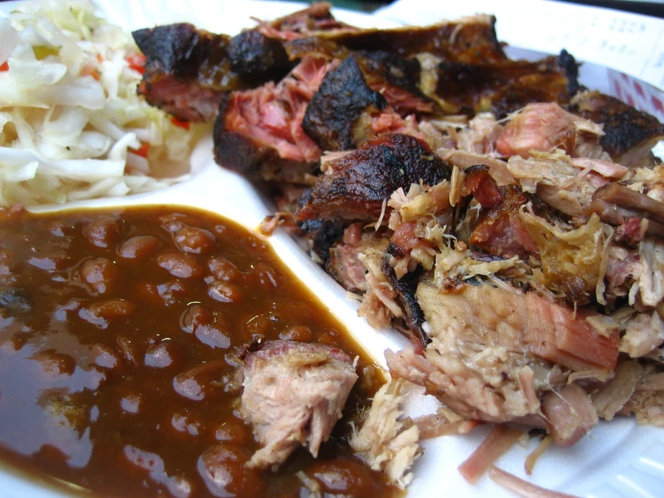 meat and rice is sitting on a paper plate