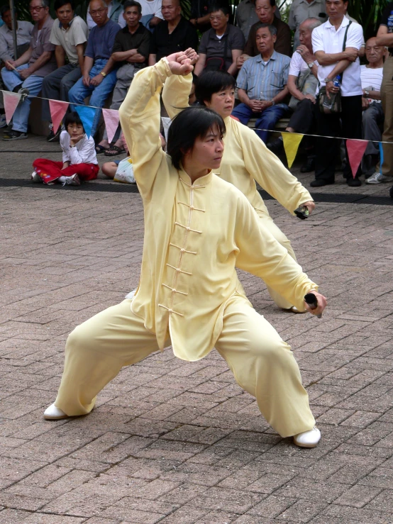 two performers in yellow taito suits and chinese spectators watching
